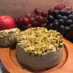 Image of a cheese wheel with pistachios and grapes