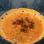 Image of a golden chowder soup with peanut garnish