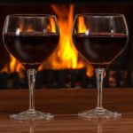 Image of two classes of merlot in front of a fire